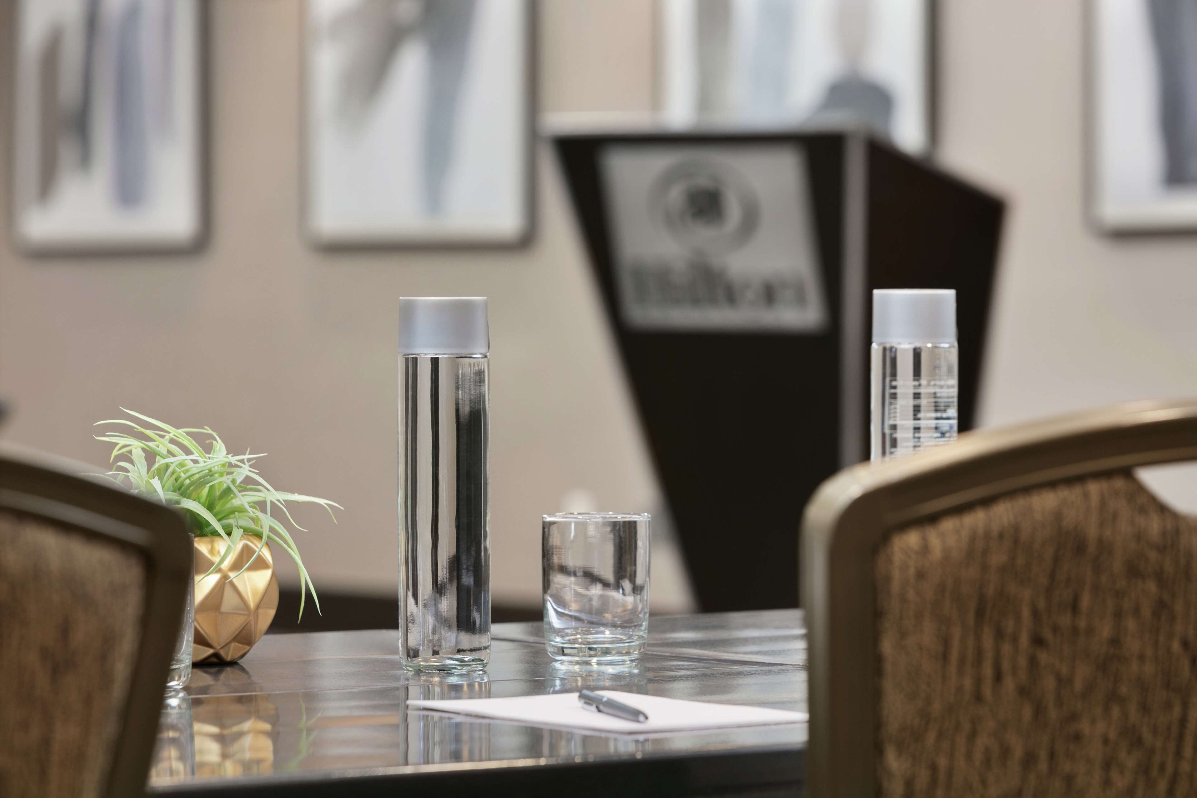 A conference table with a water bottle, a glass, and a small potted plant.