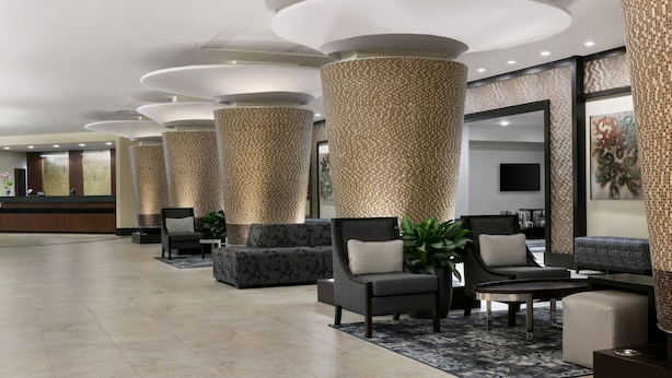 A modern lobby with a reception desk, seating area, and decorative columns.