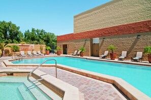 A swimming pool with lounge chairs and potted plants, surrounded by a brick wall and greenery. - Hilton Orlando/Altamonte Springs (Altamonte Springs)