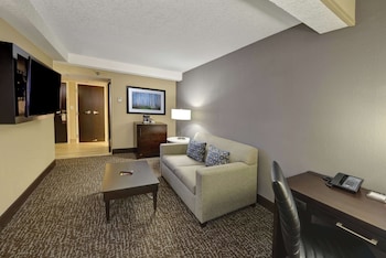 A hotel room with a bed, a desk with a chair, a dresser, a television, and a framed picture on the wall. at Hilton Orlando/Altamonte Springs