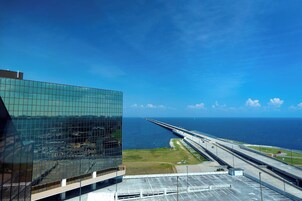 Un edificio moderno con fachada de vidrio que da a una carretera costera y al océano.