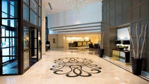 Un vestíbulo amplio con una lámpara moderna, un mostrador de recepción y un diseño decorativo en el suelo.