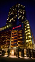 Edificio de un hotel Marriott de noche, con ventanas iluminadas y un letrero llamativo.