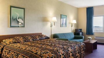 A hotel room with a large bed, a sofa, two wall-mounted lamps, and a window with a view.