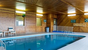 Piscina interna con pareti in legno, scaletta e cartello che indica le procedure di emergenza.