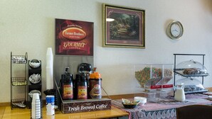 Angolo caffè con cartello che indica caffè appena preparato, distributori di caffè e esposizione di chicchi di caffè.