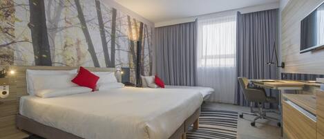 A modern hotel room with a large bed, a desk, and a TV.