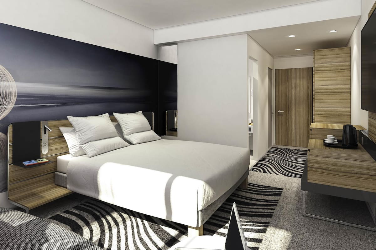 Una habitación de hotel moderna con una cama grande, mesitas de noche, un escritorio y un televisor de pantalla plana.