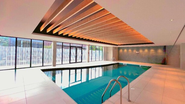 Ein Indoor-Pool mit modernem Design, der ein geneigtes Dach und große Fenster aufweist.