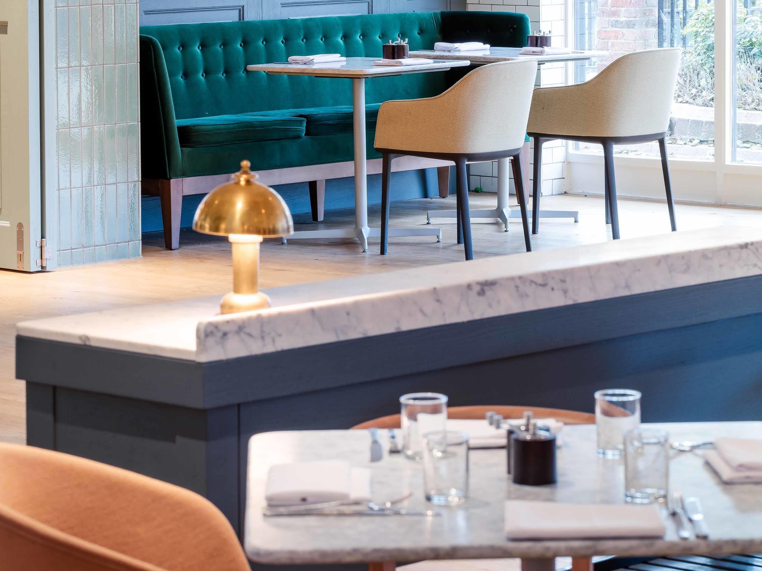 A restaurant with a green upholstered booth, a marble counter, and two chairs.