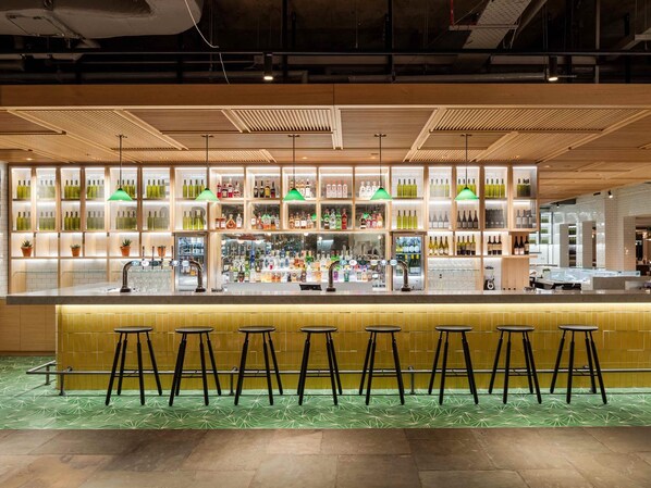 A bar area with stools, shelves of bottles, and a counter.