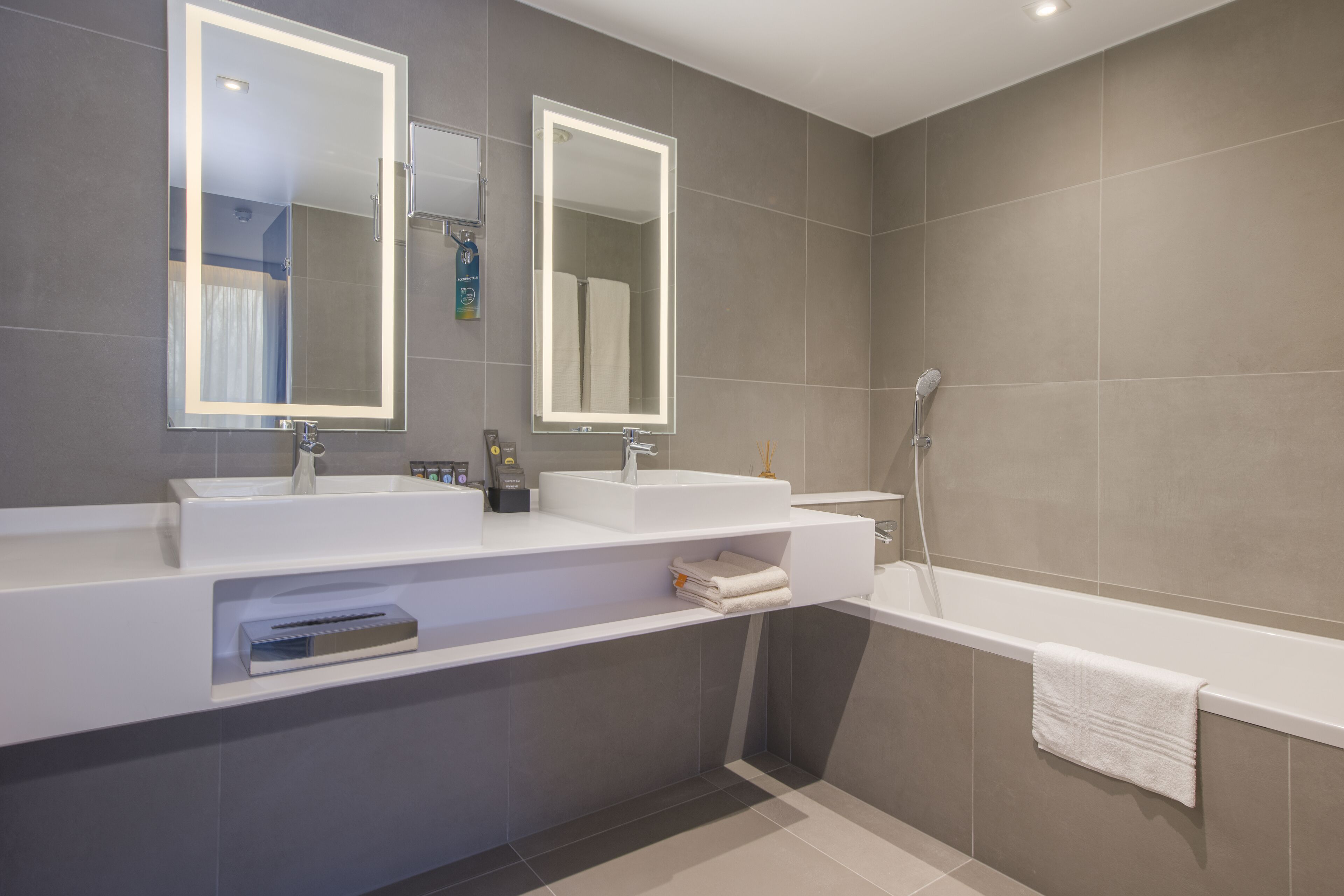 Une salle de bain moderne avec deux lavabos, une baignoire et un grand miroir.