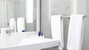 A modern bathroom with a white sink, a mirror, and two white towels hanging on a towel rack.