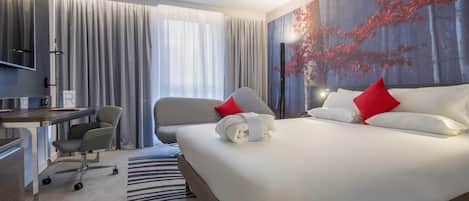 Una habitación de hotel con cama, escritorio, silla y un ventanal con cortinas.