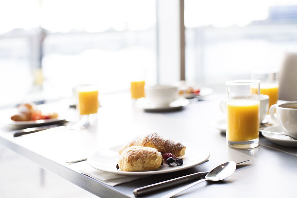 Uma mesa de café da manhã com croissants, mirtilos e suco de laranja.