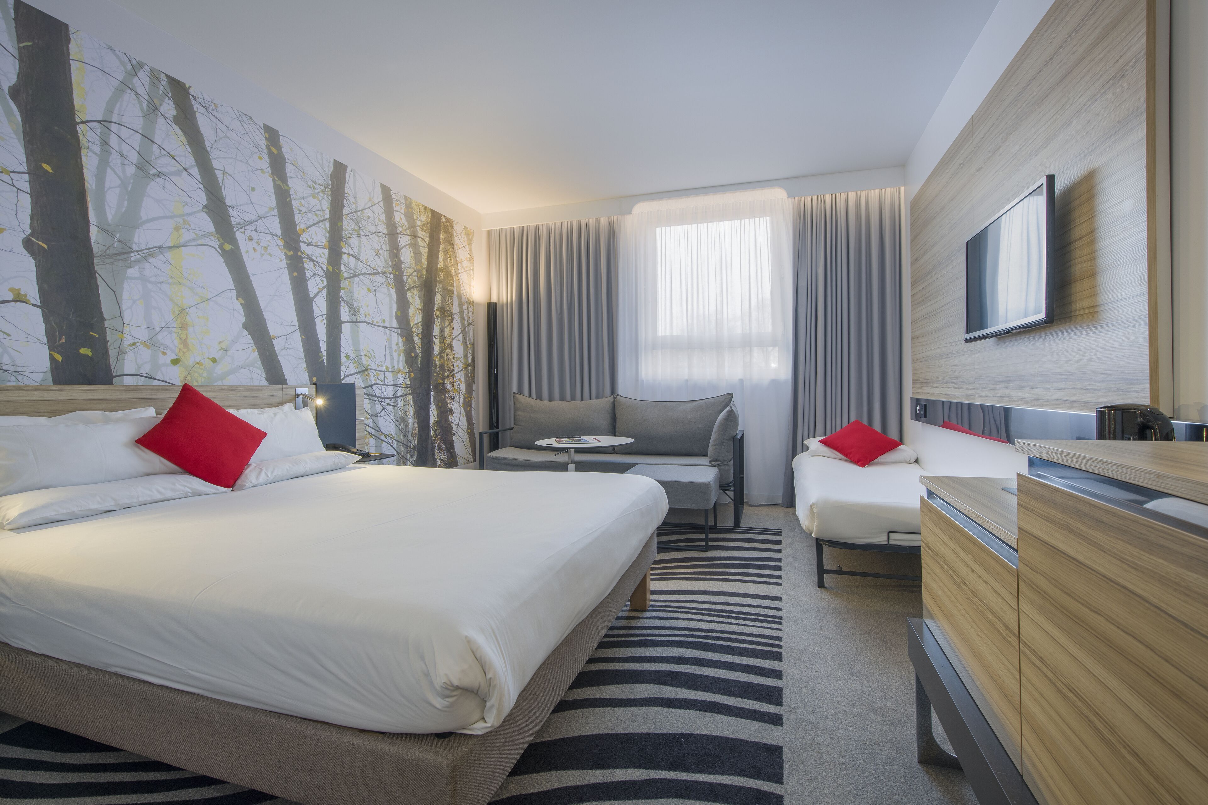 Una habitación de hotel con cama, sofá, televisión y escritorio.