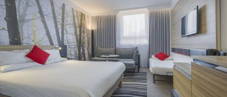 Una habitación de hotel con cama, sofá, televisión y escritorio.