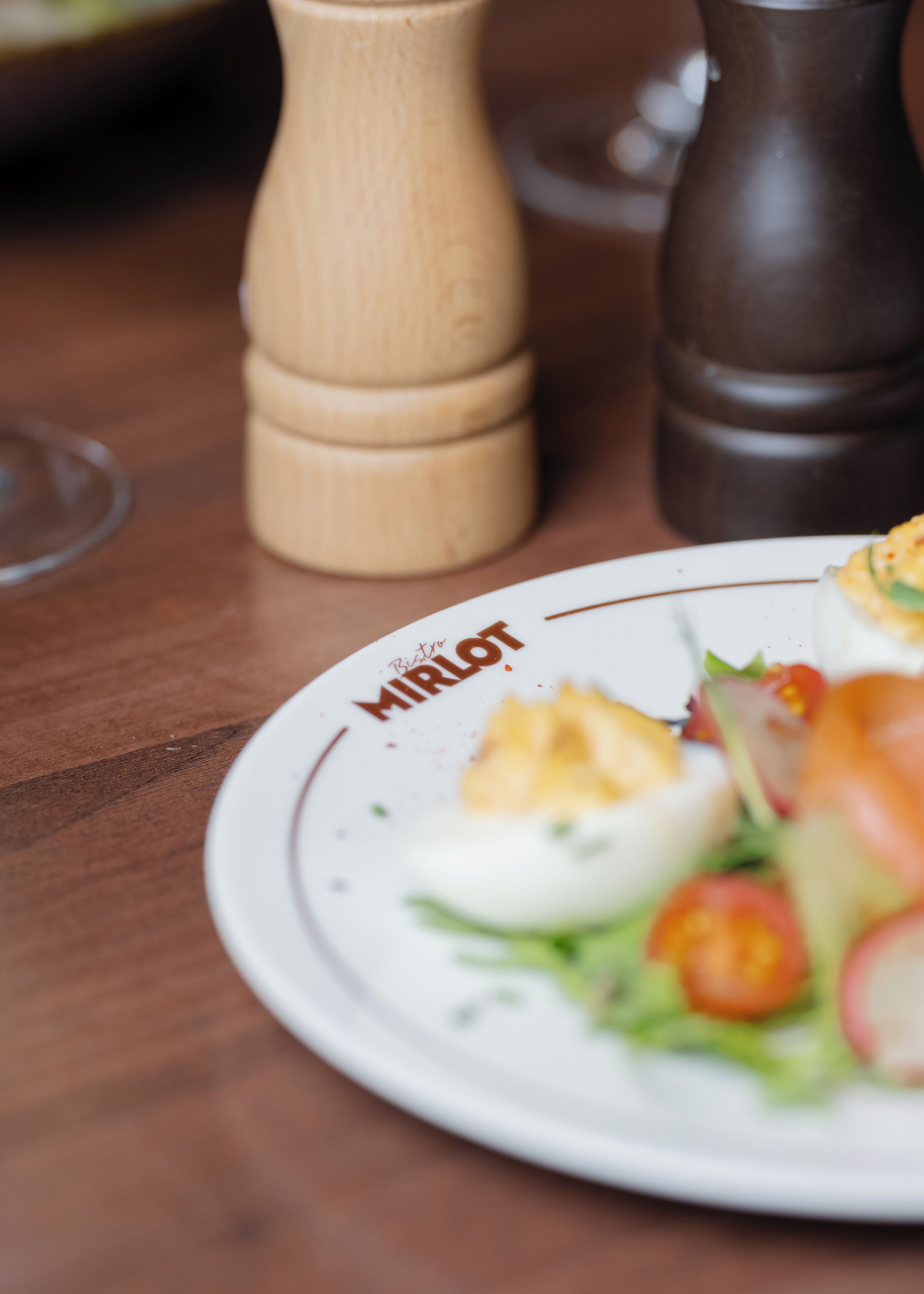 Un plato con ensalada y salero de madera sobre una mesa de madera.