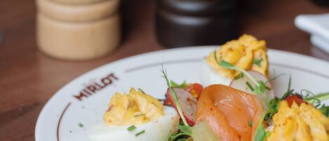A plate of food with eggs, tomatoes, radishes, and greens.
