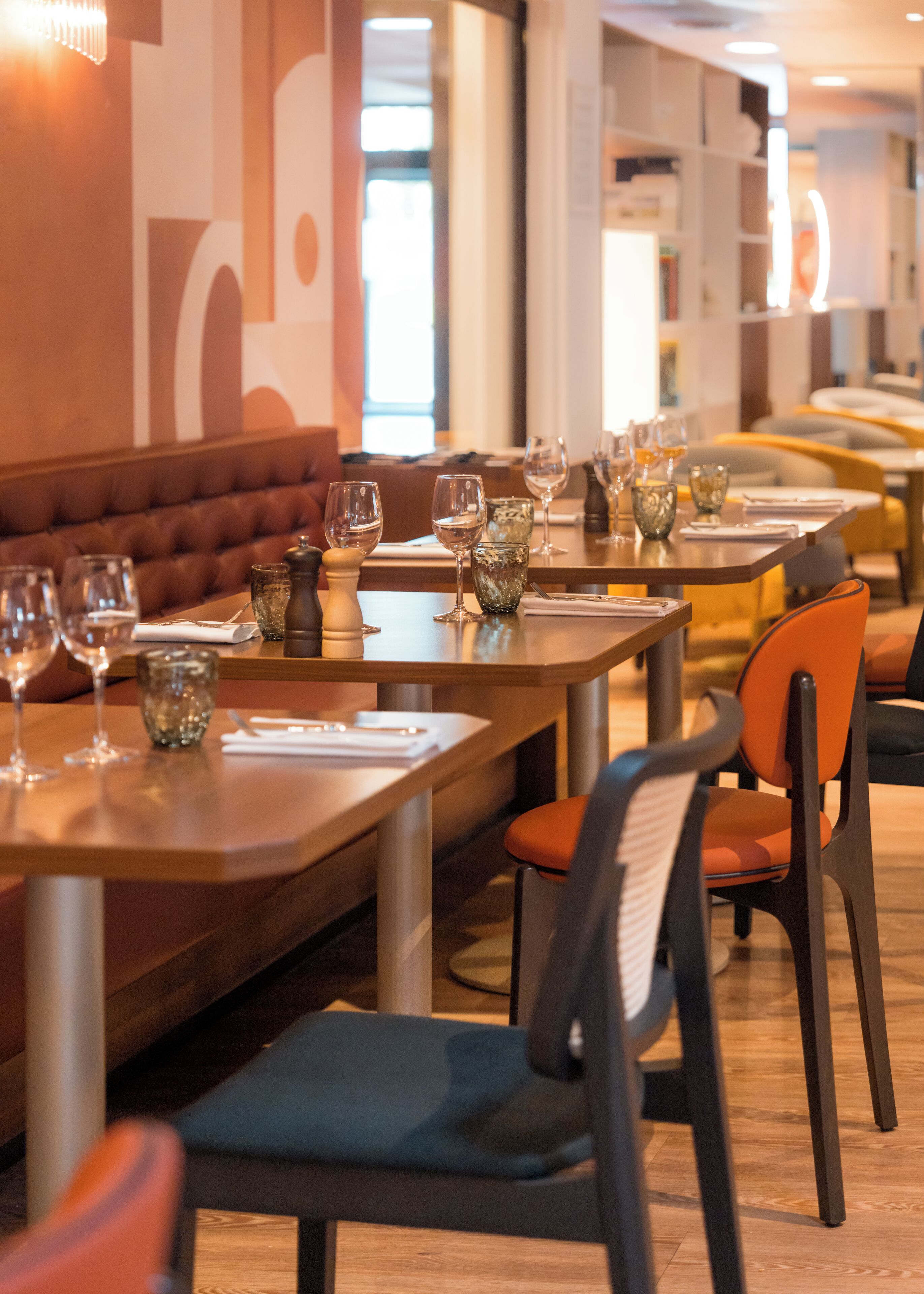 A restaurant interior with multiple tables and chairs, some with wine glasses and water glasses on them.