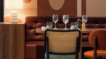 A modern dining area with a leather sofa, a round table with wine glasses, and a lamp on a side table.