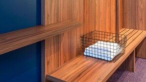 A wooden bench with a wire basket containing a white object, against a wooden wall with a blue accent.