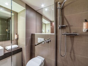 A modern bathroom with a glass shower enclosure, a toilet, and a towel rack. - Mercure Caen Cote de Nacre Herouville Saint Clair (Herouville-Saint-Clair)