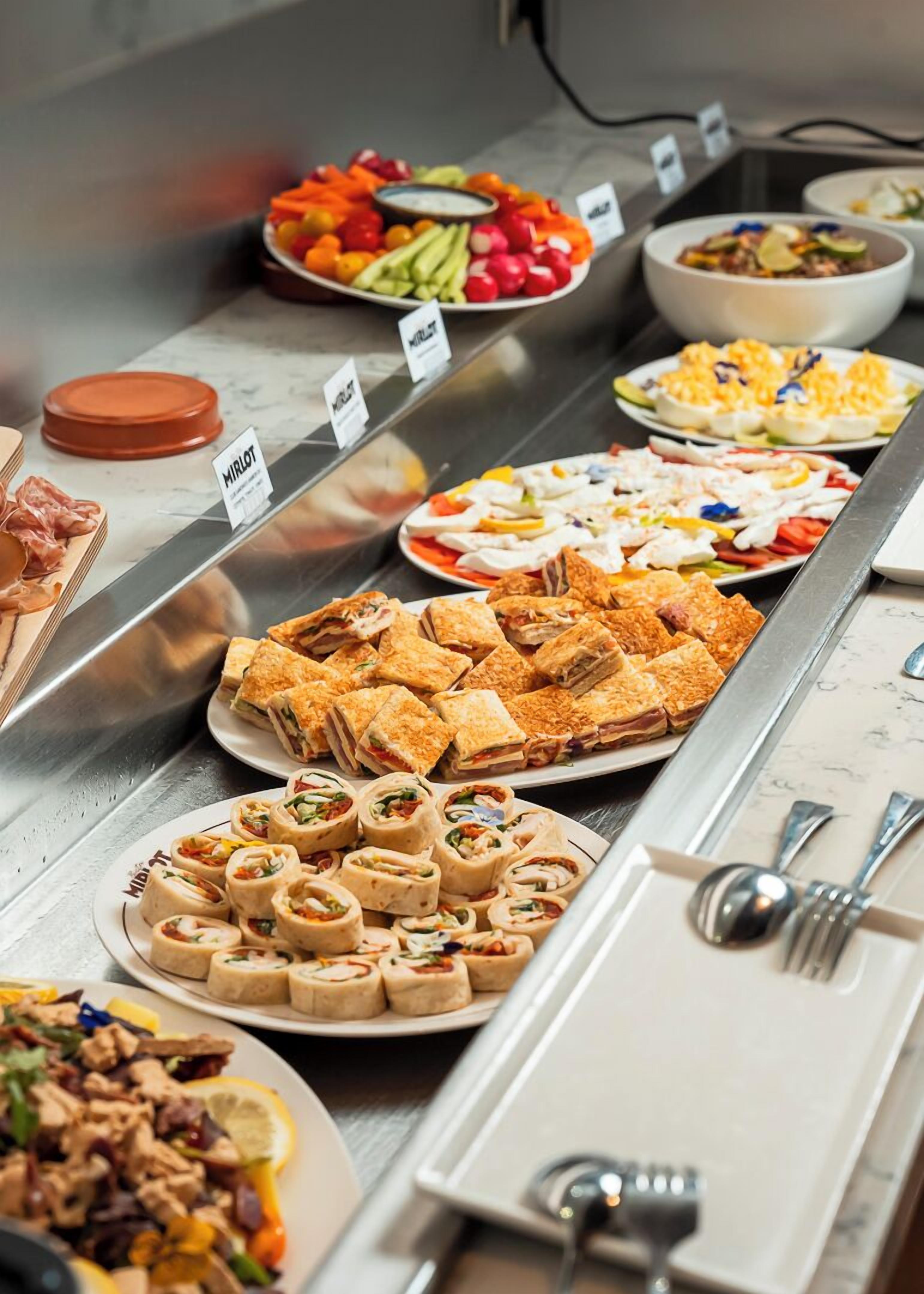 A buffet with various food options including salads, sandwiches, and a meat dish.