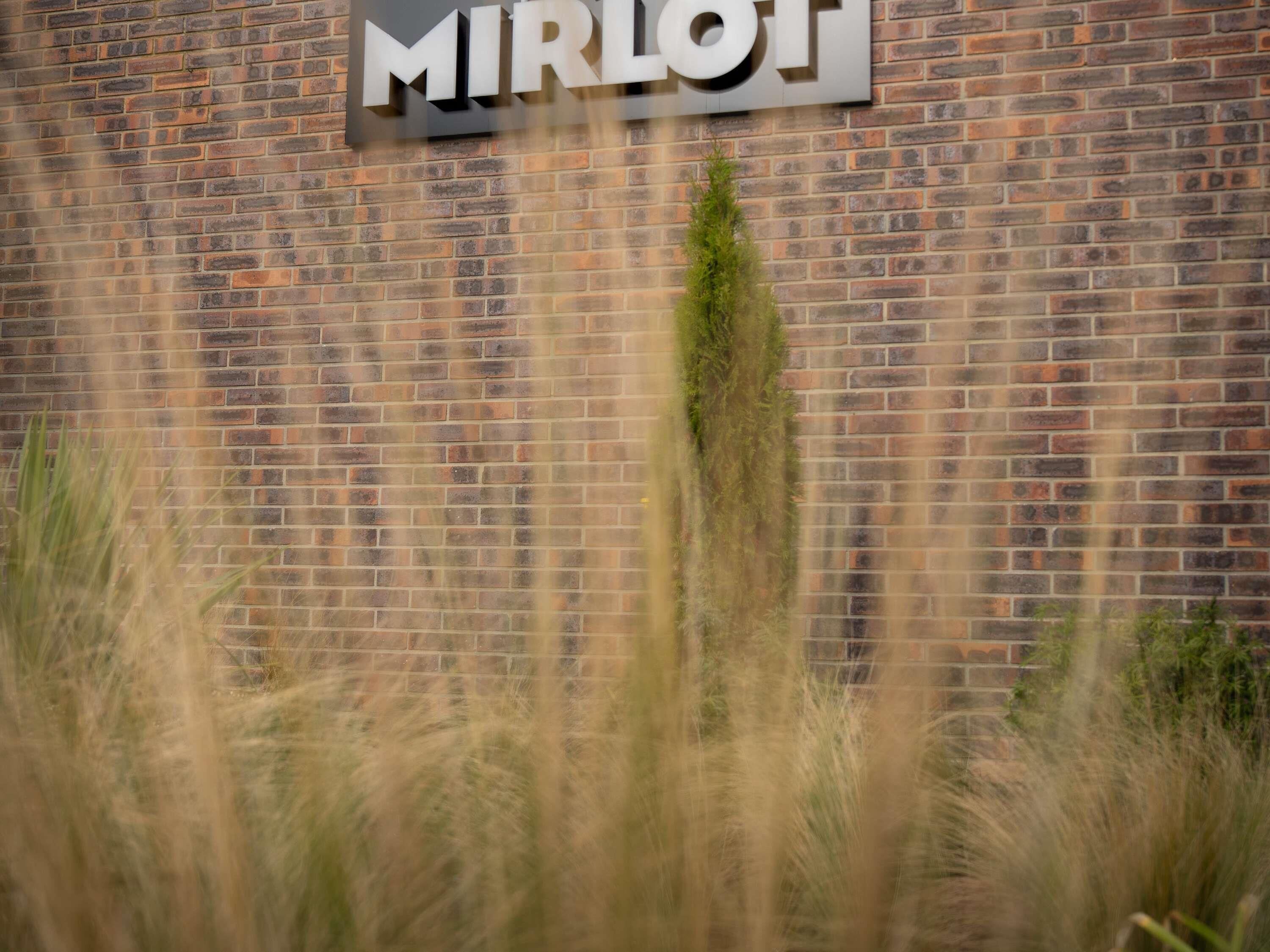 A brick wall with a sign that reads 'MIRLOJ'.