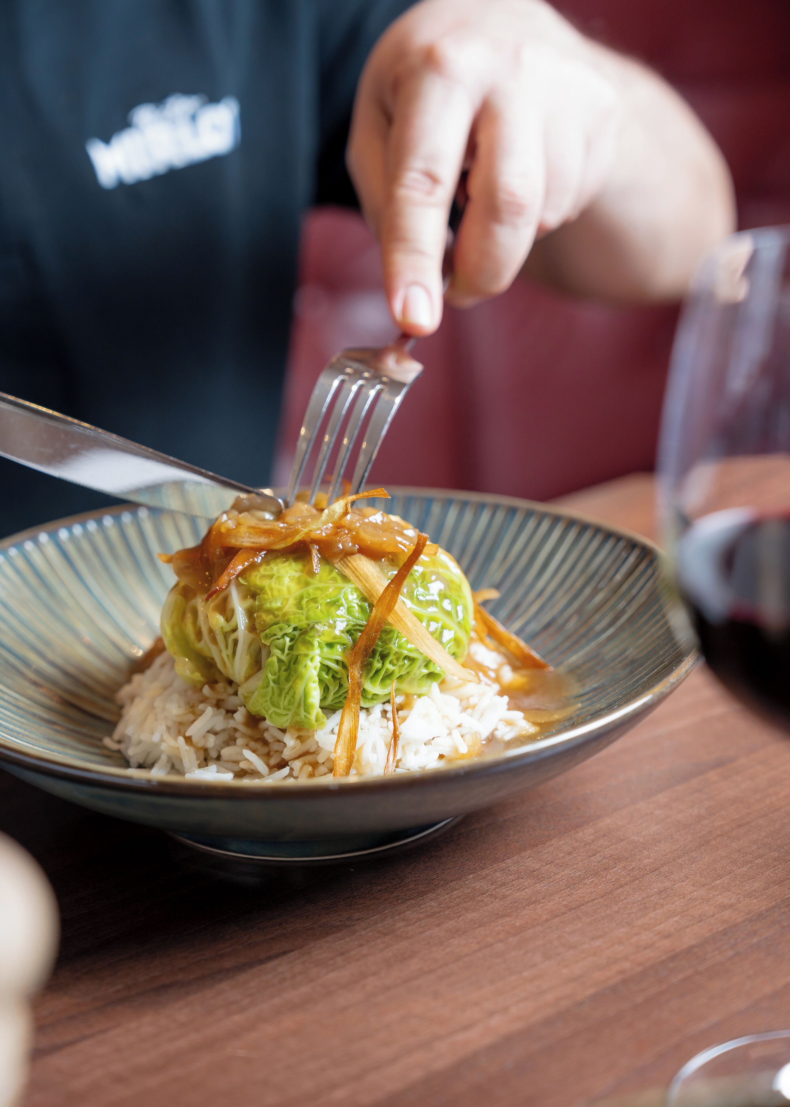 A person holding a fork over a bowl of rice and vegetables.