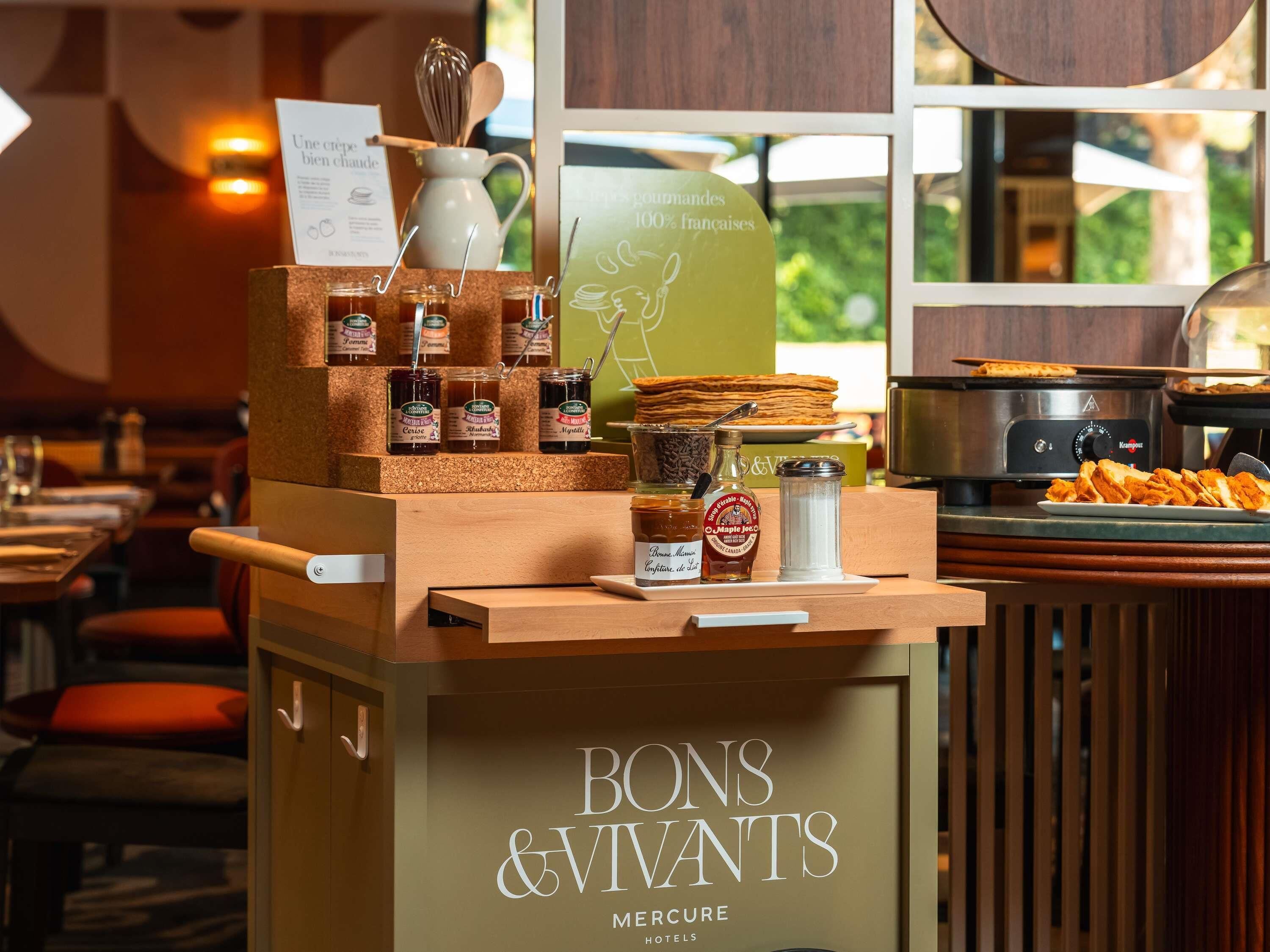A buffet setup with various food items and condiments at Bons & Vivants Mercure Hotels.