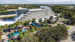 A large hotel with multiple floors, a swimming pool, and palm trees. - DoubleTree by Hilton Deerfield Beach Boca Raton (Deerfield Beach)