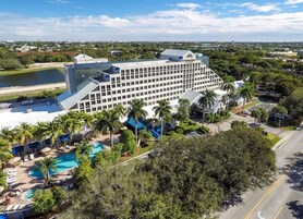 Un hotel grande con varios pisos, piscina y palmeras.