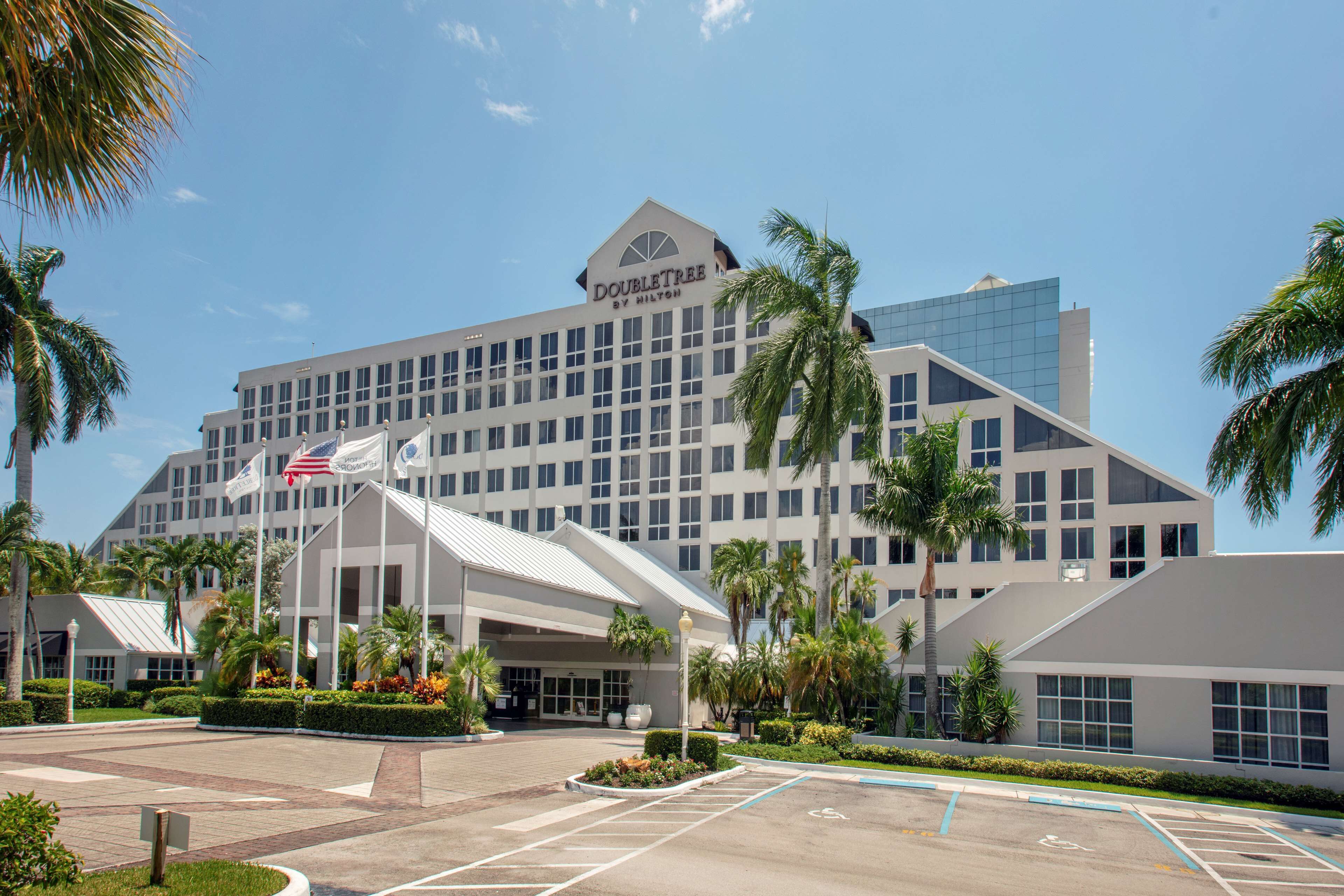 Un hotel de diseño moderno, con una entrada destacada, un área cubierta y palmeras al frente.