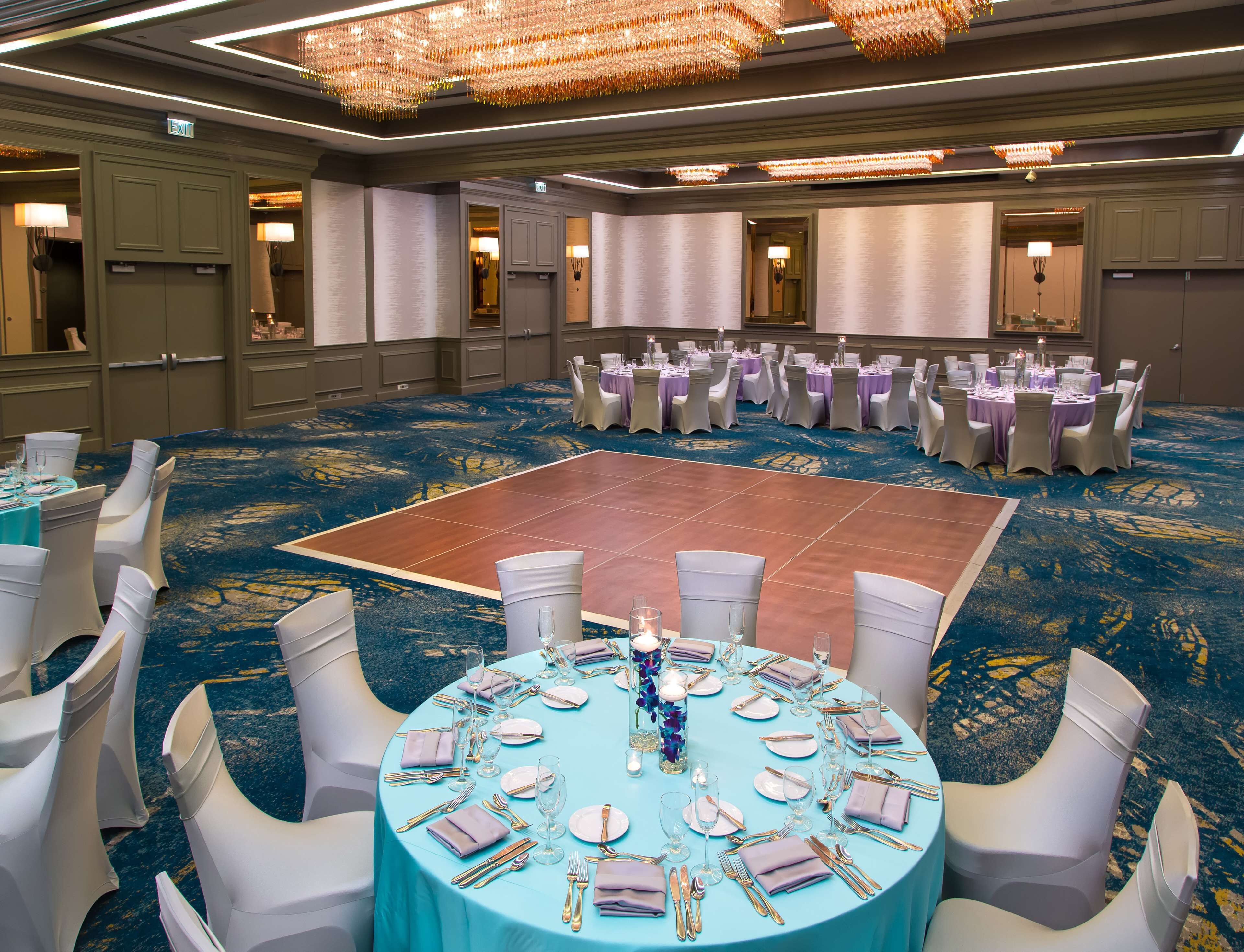A banquet hall with round tables set for a formal event, featuring a central dance floor.