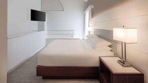 A modern hotel room with a large bed, bedside lamps, a flat-screen TV, and a large window. - DoubleTree by Hilton Deerfield Beach Boca Raton (Deerfield Beach)