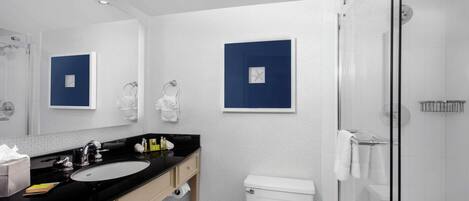 A modern bathroom with a black sink, white toilet, and glass shower enclosure.