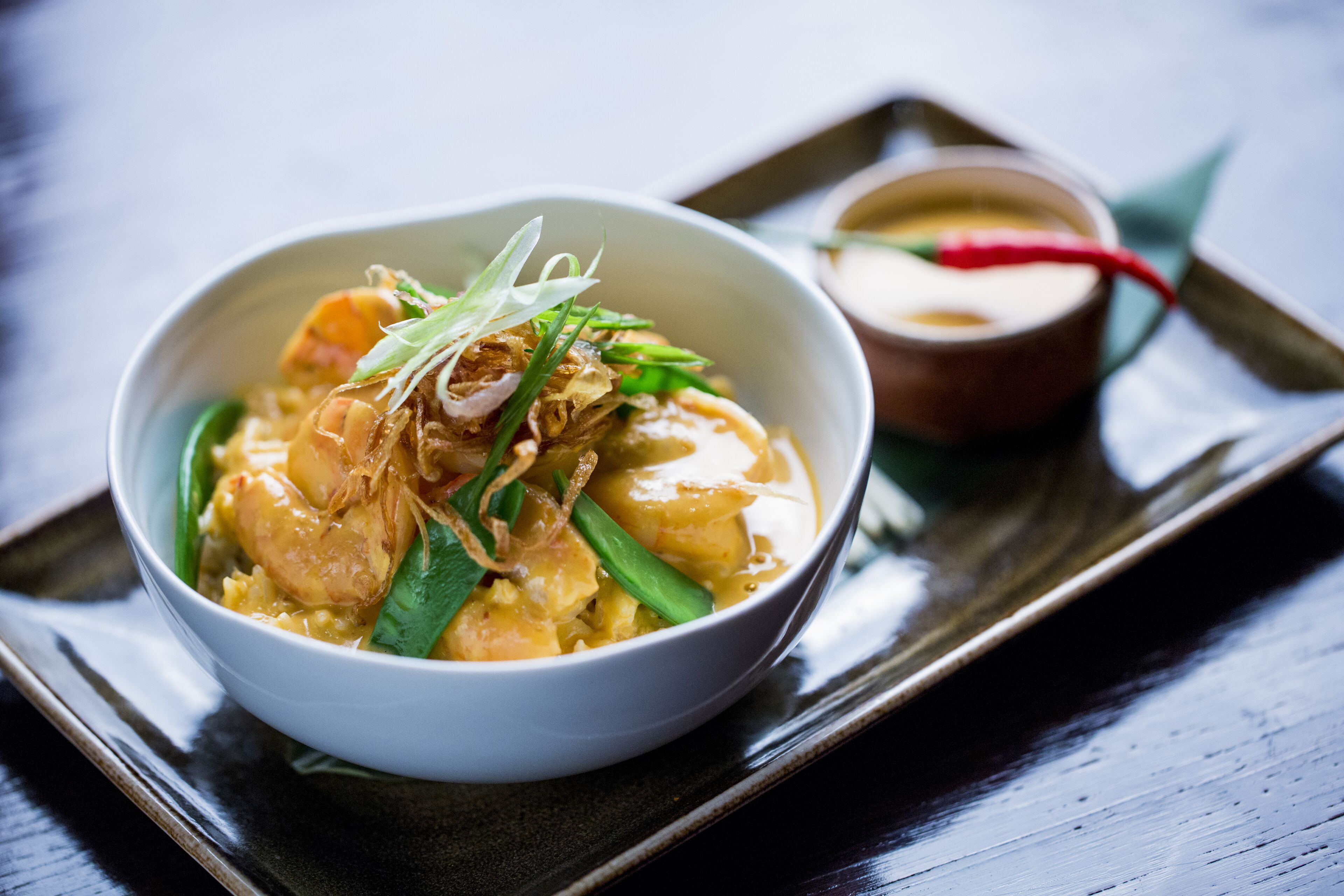 A bowl of food with a side dish on a tray.