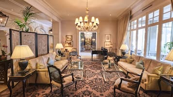 A spacious living room with a grand chandelier, plush sofas, and a piano.