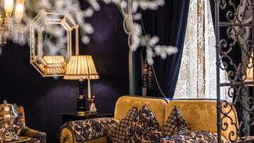 A luxurious room with a dark blue sofa, ornate side tables, and a decorative lamp.