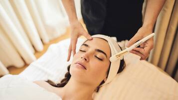 Una persona recostada en una cama recibiendo un tratamiento facial.
