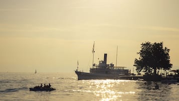 A boat with passengers and a docked ship, both on calm water.