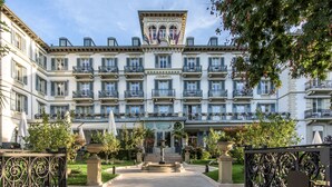 Un grand hôtel à plusieurs étages, doté d’une entrée principale, de balcons et d’un jardin bien entretenu.