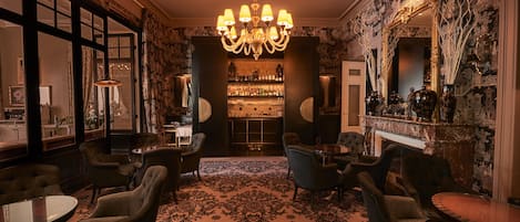 A bar area with a chandelier, bar stools, and a patterned carpet.