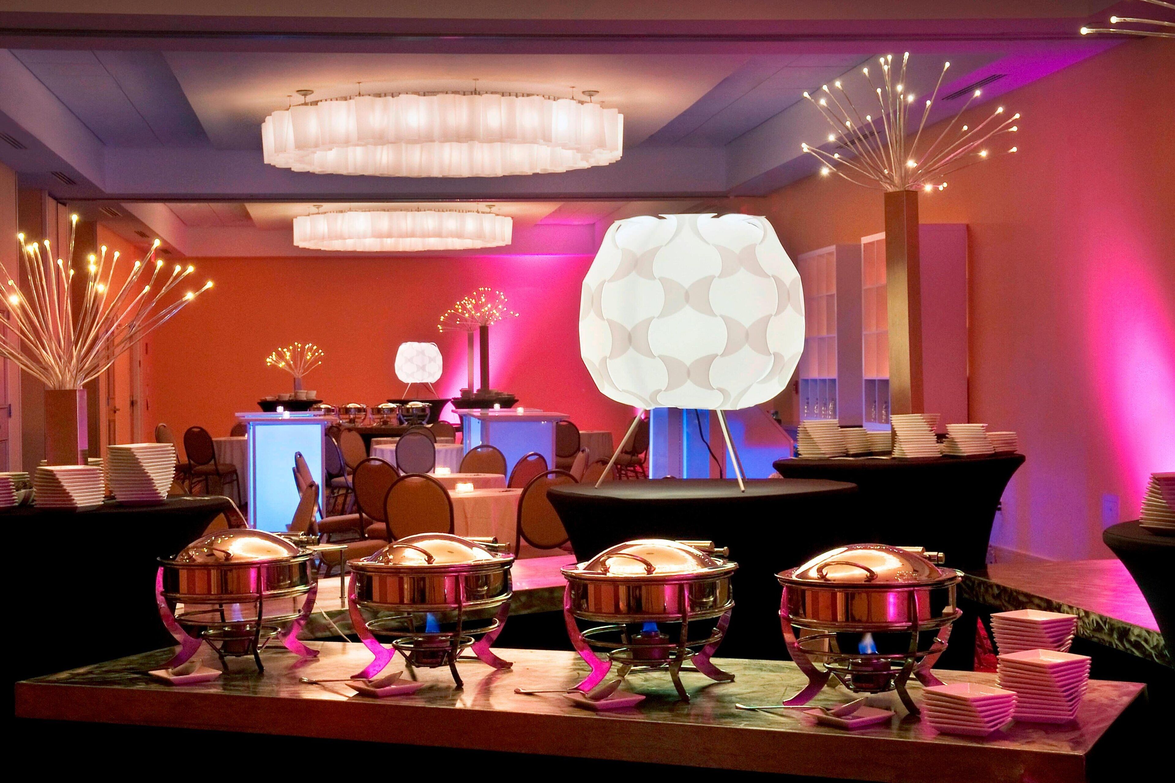 A buffet setup with multiple serving stations, a decorative light fixture, and a modern interior design.