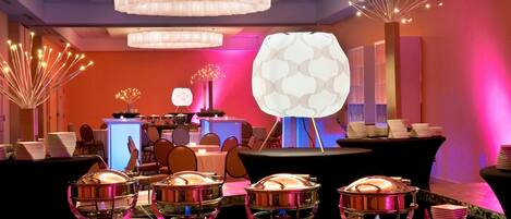 A buffet setup with multiple serving stations, a decorative light fixture, and a modern interior design.
