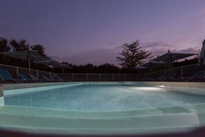 Una piscina al aire libre de temporada, sombrillas