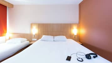 A hotel room with a large bed, two bedside tables, and two wall-mounted lamps.