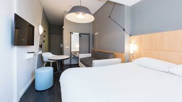 A modern hotel room with a bed, a desk, a chair, and a hanging light fixture.