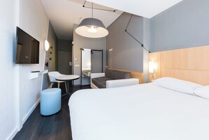 Habitación de hotel moderna con una cama, un escritorio, una silla y una lámpara colgante.